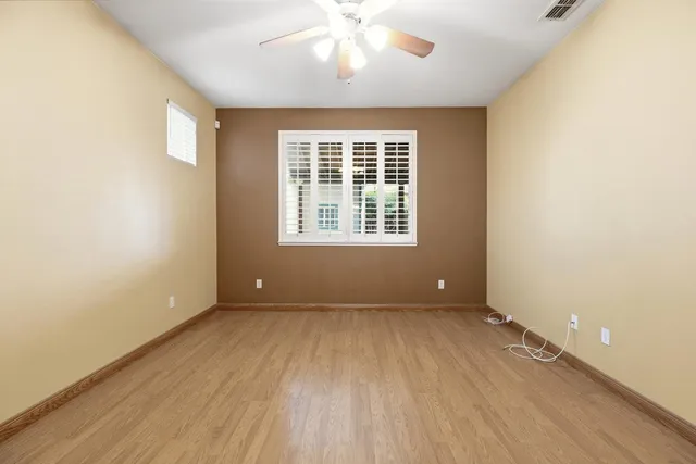 a view of an empty room with a window and wooden floor