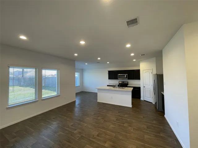 a view of a kitchen and an empty room with wooden floor