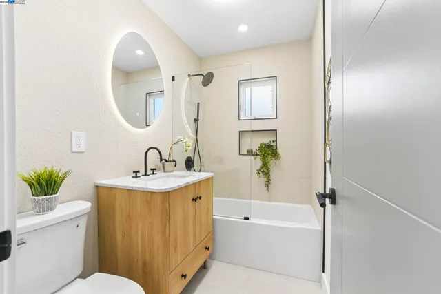 a view of a hallway with wooden floor and a bathroom