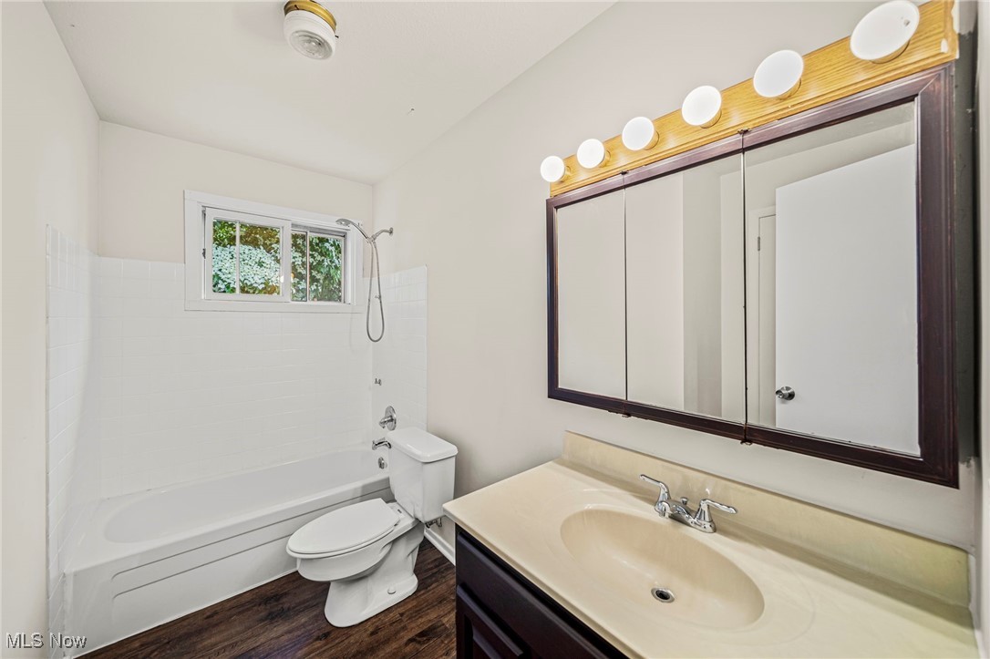 1816 Red Bird Road Madison, OH 44057 - Photo 14 of 24 Bathroom featuring toilet, vanity, wood finished floors, and shower / washtub combination