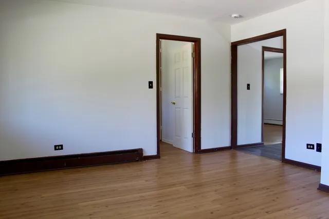 a view of an empty room with wooden floor and closet