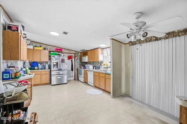 a kitchen that has a lot of white cabinets and stainless steel appliances