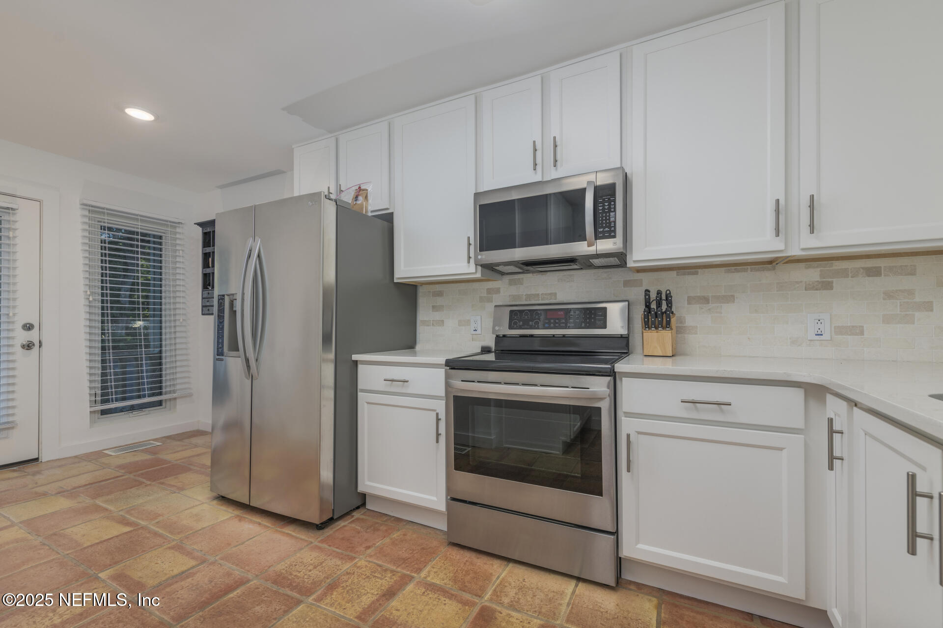 3426 Sea Marsh Road Fernandina Beach, FL 32034 - Photo 38 of 39 a kitchen with stainless steel appliances white cabinets a stove a microwave and a refrigerator
