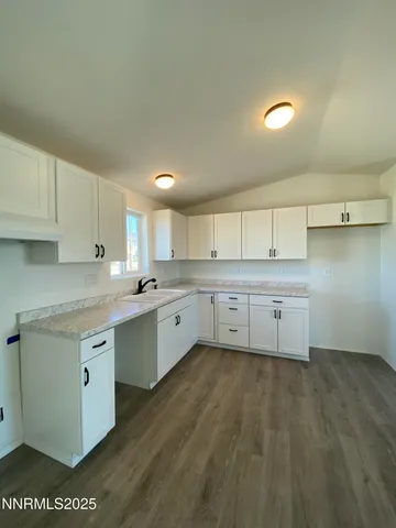 a kitchen with granite countertop a sink cabinets and wooden floor