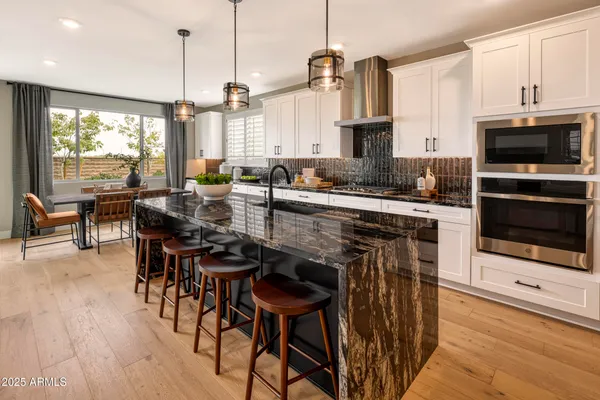 a kitchen with stainless steel appliances a table chairs stove and microwave