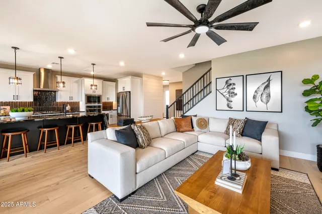 a living room with furniture kitchen view and a wooden floor