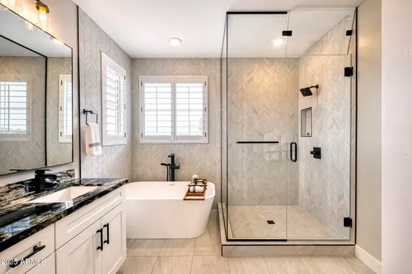 a bathroom with a granite countertop bathtub shower sink and mirror