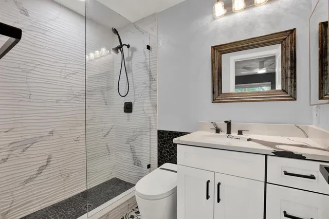 a bathroom with a granite countertop toilet sink and mirror