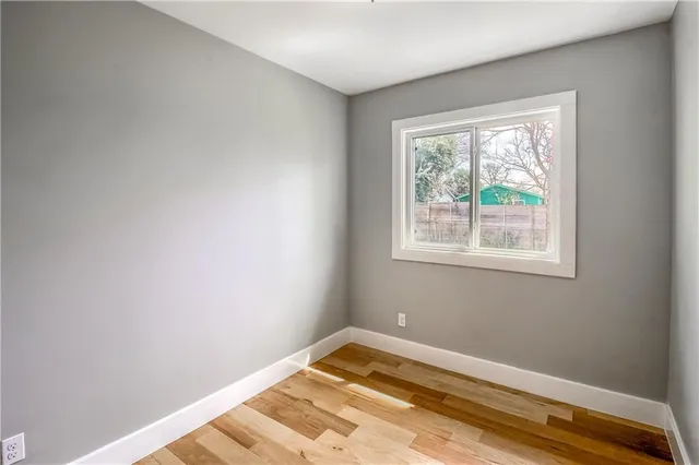 a view of a bedroom with wooden floor and a window