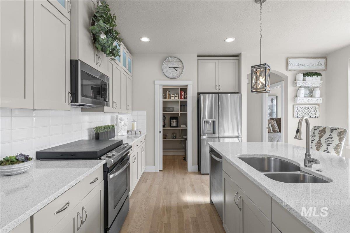 2856 South Wise Way Boise, ID 83716 - Photo 17 of 47 Kitchen with stainless steel appliances, pendant lighting, light stone counters, light wood-type flooring, and a textured ceiling