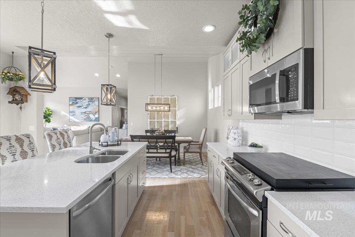 2856 South Wise Way Boise, ID 83716 - Photo 19 of 47 Kitchen with stainless steel appliances, light stone counters, pendant lighting, a textured ceiling, and an island with sink