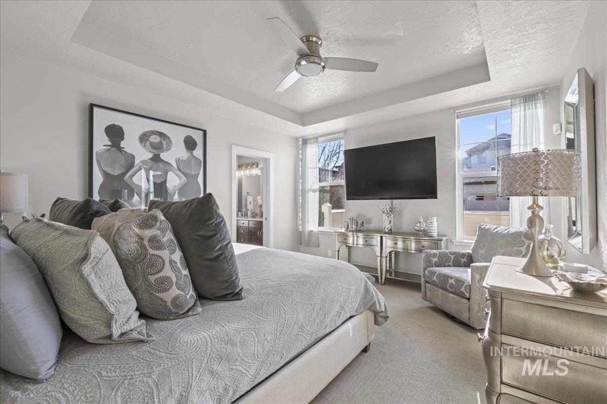 2856 South Wise Way Boise, ID 83716 - Photo 20 of 47 Carpeted bedroom featuring a tray ceiling, ensuite bath, ceiling fan, and a textured ceiling