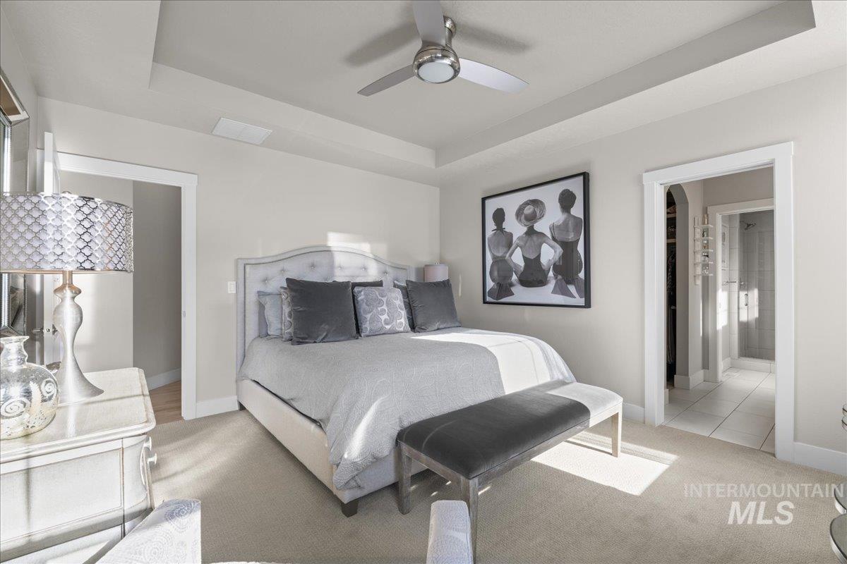 2856 South Wise Way Boise, ID 83716 - Photo 21 of 47 Carpeted bedroom with a tray ceiling, a ceiling fan, and ensuite bathroom