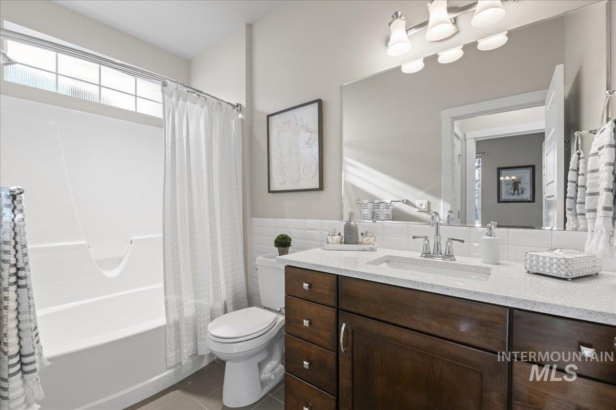 2856 South Wise Way Boise, ID 83716 - Photo 25 of 47 Full bathroom with shower / bathtub combination with curtain, vanity, tile walls, light tile patterned floors, and a wainscoted wall