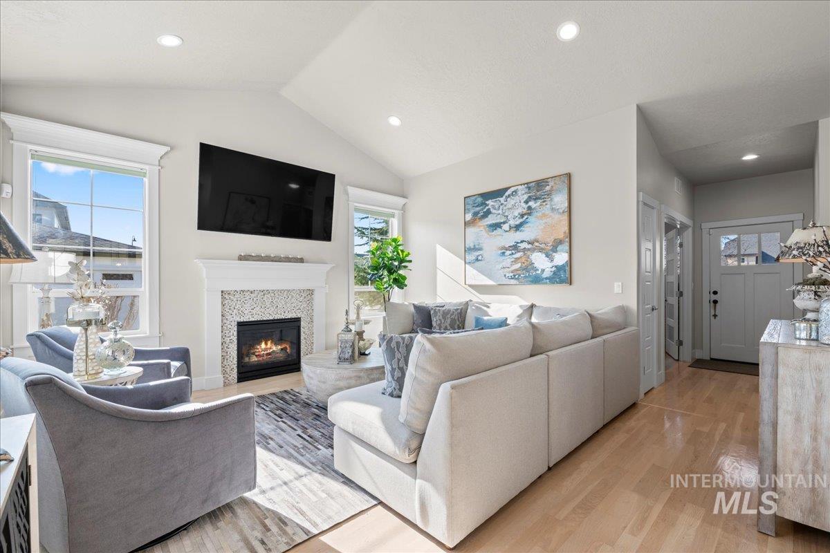 2856 South Wise Way Boise, ID 83716 - Photo 8 of 47 Living area featuring light wood finished floors, vaulted ceiling, healthy amount of natural light, a glass covered fireplace, and recessed lighting