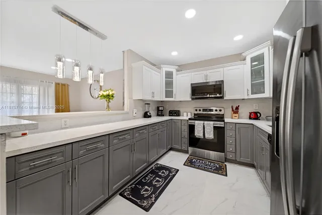 a kitchen with granite countertop a refrigerator a sink a stove top oven a counter space and cabinets