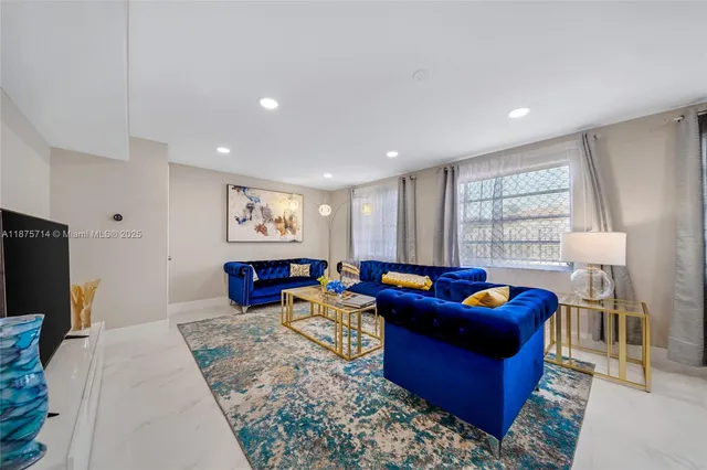 a living room with furniture a flat screen tv and a refrigerator