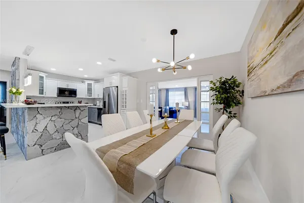 a living room with furniture kitchen view and a chandelier
