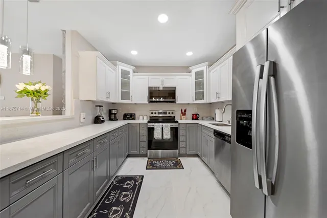 a white kitchen with stainless steel appliances and a refrigerator