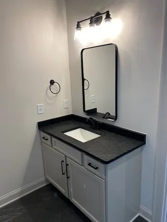 a bathroom with a granite countertop sink and a mirror