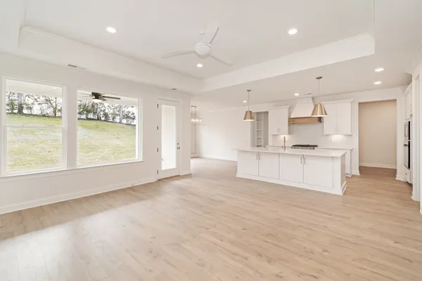 a view of large kitchen with granite countertop stainless steel appliances stove refrigerator and cabinets