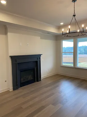 an empty room with wooden floor fireplace and windows
