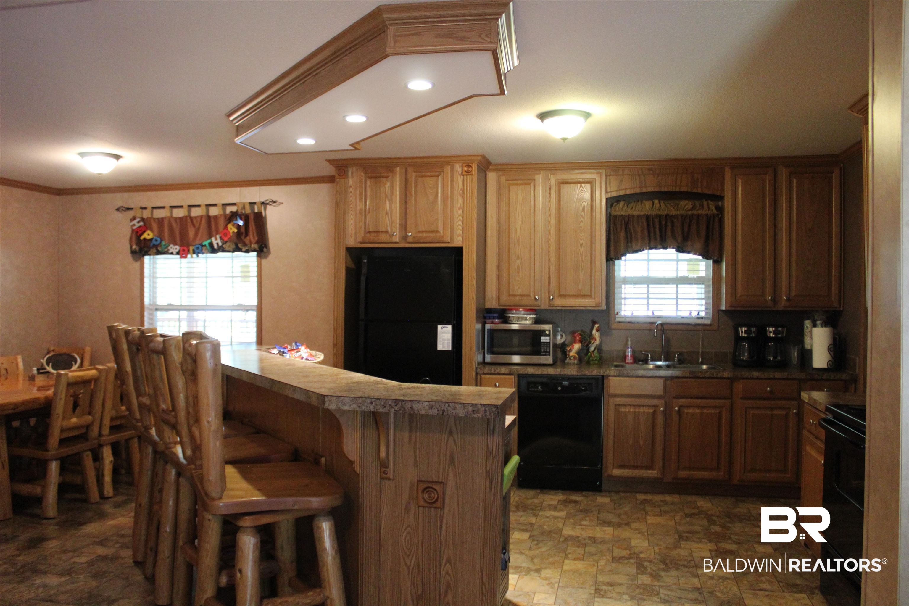 7258 Henderson Road Lowndesboro, AL 36752 - Photo 10 of 22 Kitchen featuring stone finish floors, recessed lighting, black appliances, a breakfast bar, and crown molding