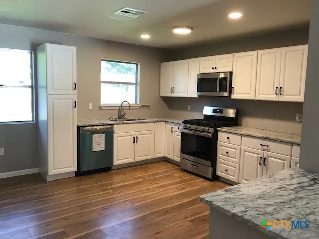 a kitchen with stainless steel appliances granite countertop a stove a microwave and white cabinets