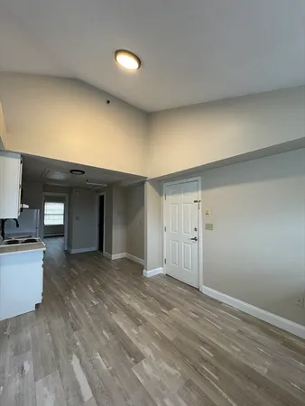 a view of a livingroom with wooden floor and kitchen space