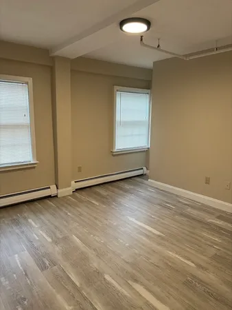 an empty room with wooden floor and windows
