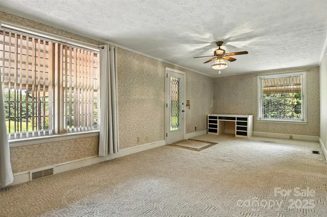 an empty room with windows and ceiling fan