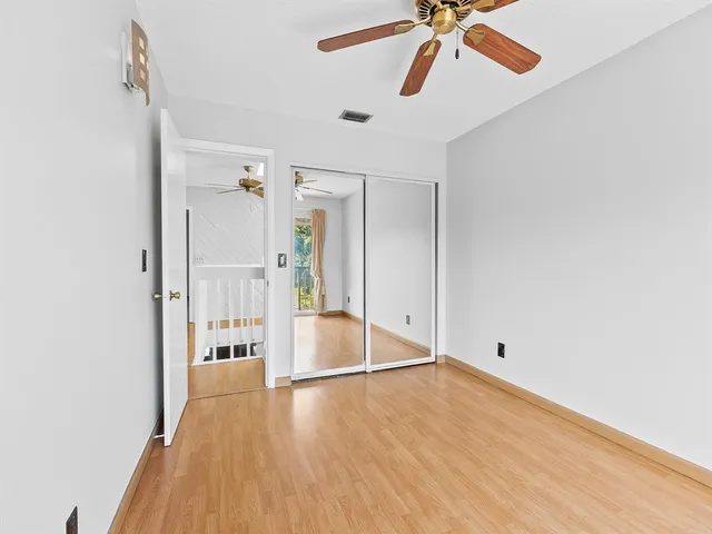 a view of a room with wooden floor and a ceiling fan