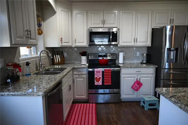 a kitchen with stainless steel appliances granite countertop a stove a sink and a microwave