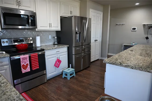 a kitchen with stainless steel appliances granite countertop a refrigerator stove and wooden floor