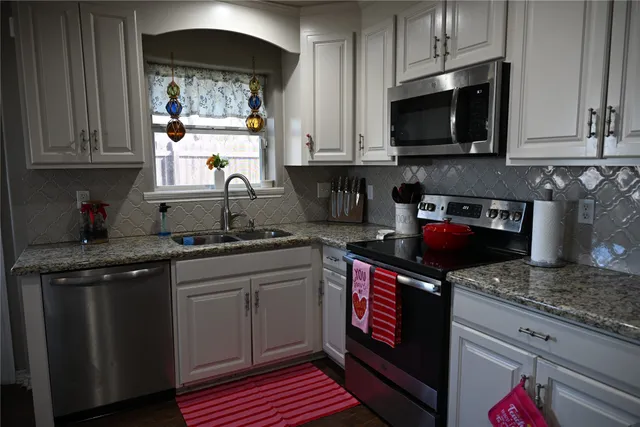 a kitchen with stainless steel appliances granite countertop a stove a sink and a microwave