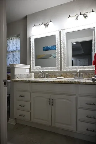 a bathroom with a granite countertop sink double vanity and mirror
