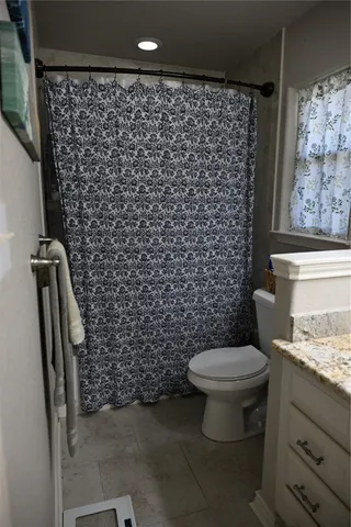 a bathroom with a granite countertop toilet and a shower