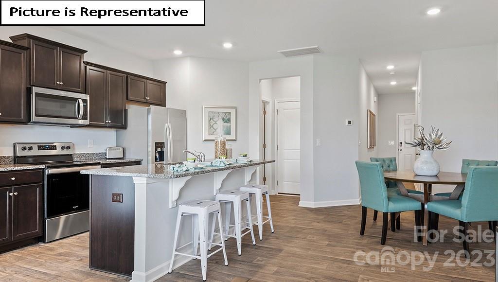 9027 Lowfalls Lane Charlotte, NC 28216 - Photo 8 of 27 a kitchen with stainless steel appliances granite countertop a stove top oven a refrigerator a sink and a dining table with wooden floor
