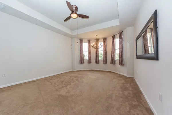 an empty room with chandelier fan and windows