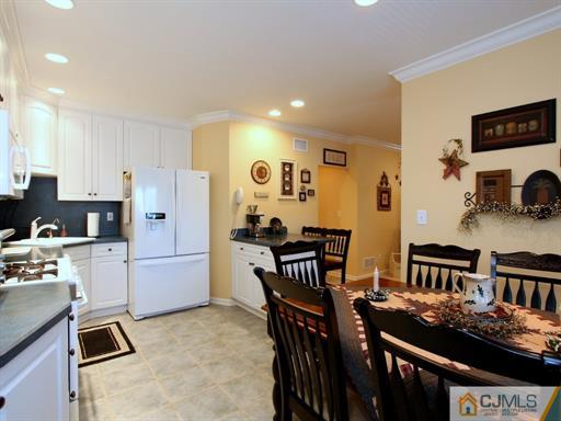 121 New Market Road Dunellen, NJ 08812 - Photo 10 of 23 a kitchen with stainless steel appliances kitchen island granite countertop a stove a refrigerator a dining table and chairs with wooden floor