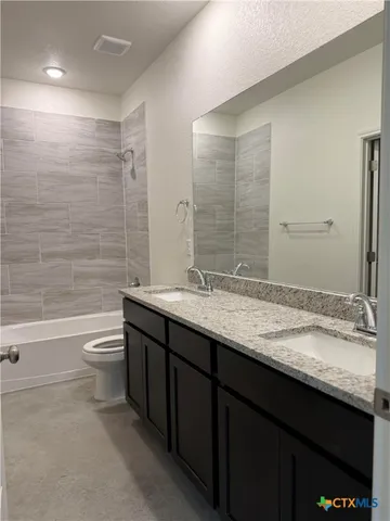 a bathroom with a granite countertop sink toilet a large mirror and bathtub
