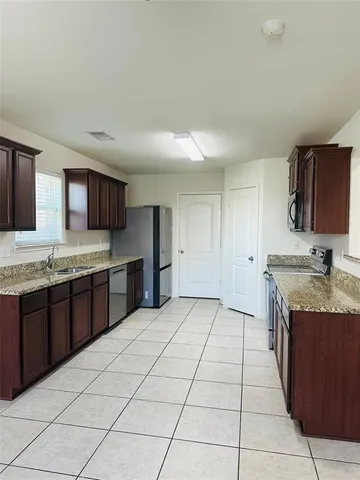 a large kitchen with granite countertop a sink and a stove