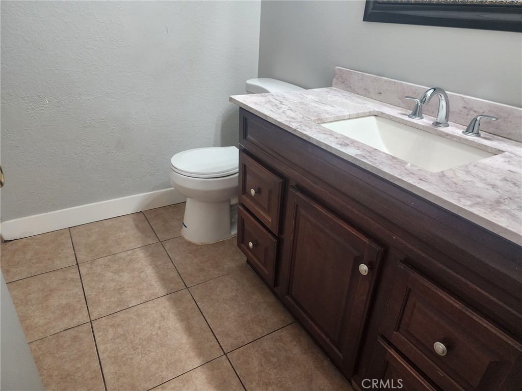 4877 Jackson Street, Unit C Riverside, CA 92503 - Photo 11 of 12 a bathroom with a granite countertop sink a toilet and mirror
