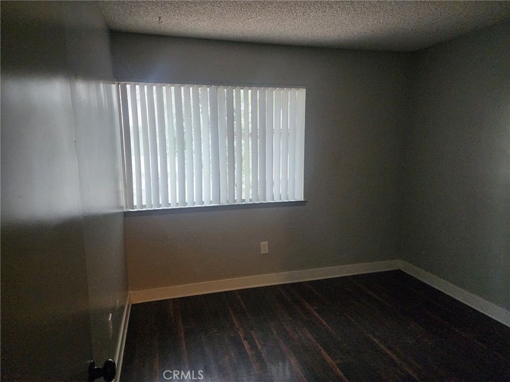 4877 Jackson Street, Unit C Riverside, CA 92503 - Photo 9 of 12 an empty room with wooden floor and windows