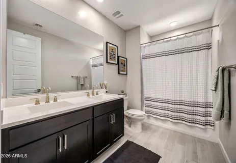 a bathroom with a double vanity sink toilet mirror and shower