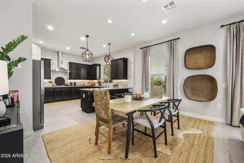 a kitchen with stainless steel appliances granite countertop a stove top oven a sink a dining table and chairs with wooden floor