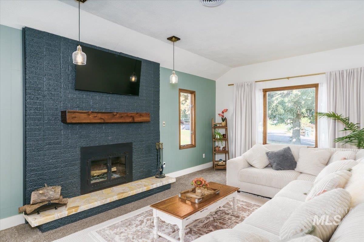 1401 Chokecherry Drive Pocatello, ID 83204 - Photo 4 of 46 Living area featuring a floor-to-ceiling brick fireplace with a wood mantel, a light-colored hearth, and two pendant lights