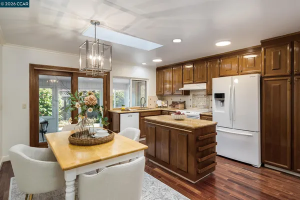 a kitchen with a refrigerator a stove a sink and a dining table with wooden floor