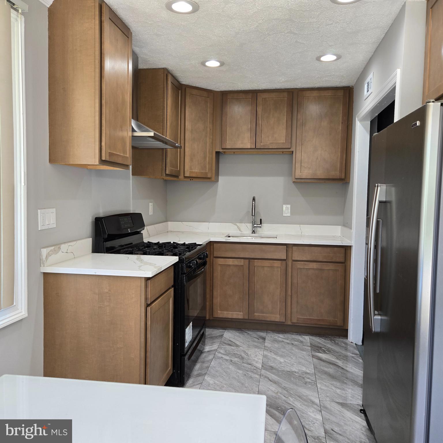 9711 Dilston Road Silver Spring, MD 20903 - Photo 15 of 44 a kitchen with stainless steel appliances granite countertop a sink a stove a refrigerator and a microwave