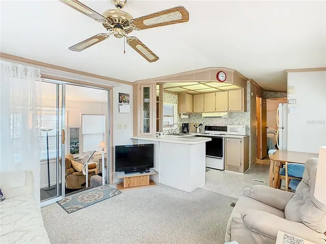 a living room with furniture a flat screen tv and a kitchen view